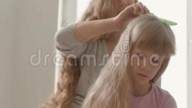 年轻女子梳着金发的女儿的特写双手。 母亲、童年、<strong>单亲</strong>的概念。 休闲